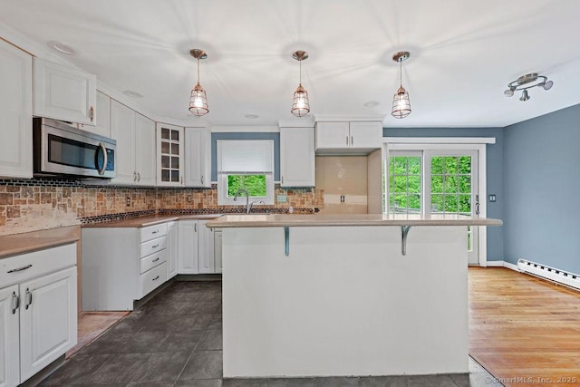 99 Redwood Dr, Bristol, CT 06010 - kitchen featuring stainless steel microwave, plenty of natural light, a baseboard radiator, and white cabinets