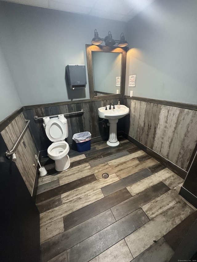 half bathroom with a wainscoted wall, hardwood / wood-style floors, and toilet