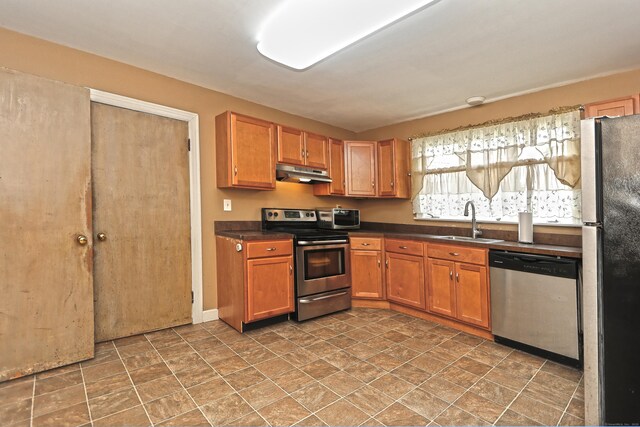 246 Ray Rd, New Haven, CT 06515 - kitchen with appliances with stainless steel finishes, under cabinet range hood, dark countertops, brown cabinetry, and stone finish flooring
