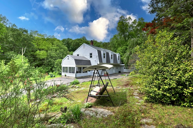 8 Whippoorwill Ln, Bethany, CT 06524 - rear view of house with a gambrel roof, a sunroom, a chimney, roof with shingles, and a forest view