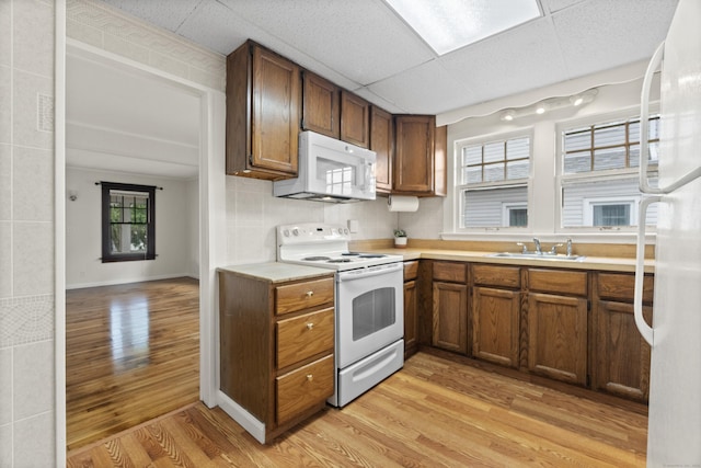 128 Grove Pl, West Haven, CT 06516 - kitchen featuring white appliances, light wood-style floors, a sink, light countertops, and brown cabinetry