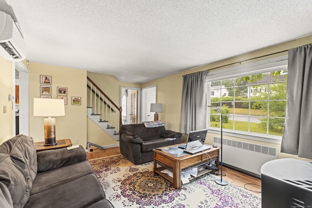 116 Maple St, Wethersfield, CT 06109 - living area with radiator, wood finished floors, a textured ceiling, a wall unit AC, and stairway