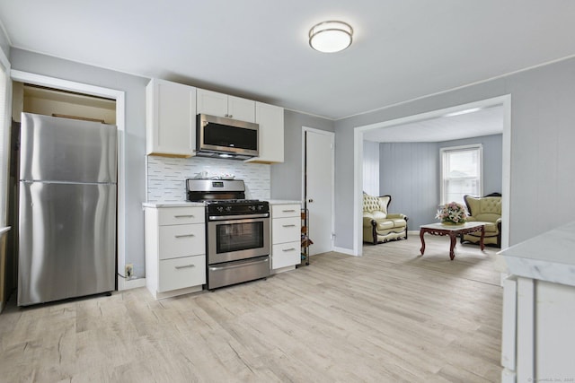 8 3rd St, Norwich, CT 06360 - kitchen featuring stainless steel appliances, light countertops, light wood-style floors, white cabinets, and decorative backsplash