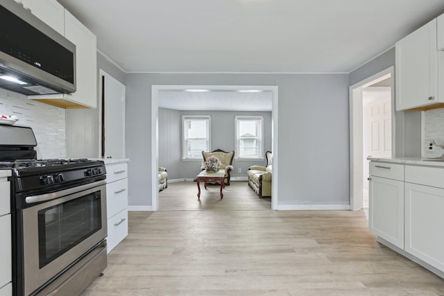 8 3rd St, Norwich, CT 06360 - kitchen with appliances with stainless steel finishes, light wood-type flooring, tasteful backsplash, white cabinets, and ornamental molding