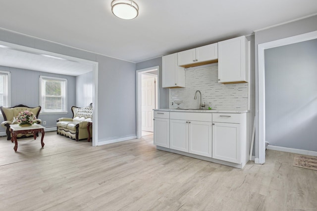 8 3rd St, Norwich, CT 06360 - kitchen with light countertops, a sink, light wood finished floors, backsplash, and white cabinetry