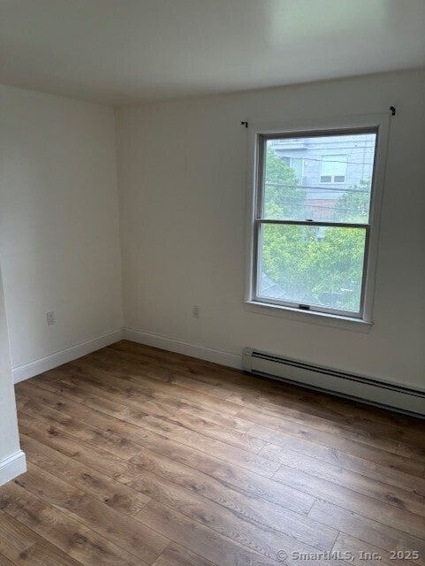 61 Clinton Ave Unit 2, Stamford, CT 06901 - unfurnished room featuring wood finished floors, a baseboard heating unit, and baseboards