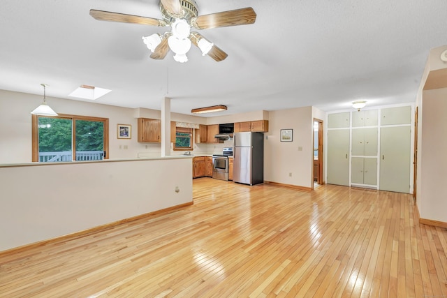 9 Cypress Ln, Trumbull, CT 06611 - unfurnished living room featuring light wood-style flooring, baseboards, a skylight, and a ceiling fan