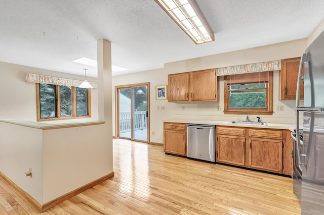 9 Cypress Ln, Trumbull, CT 06611 - kitchen with stainless steel appliances, a skylight, a sink, light wood-style flooring, and a textured ceiling