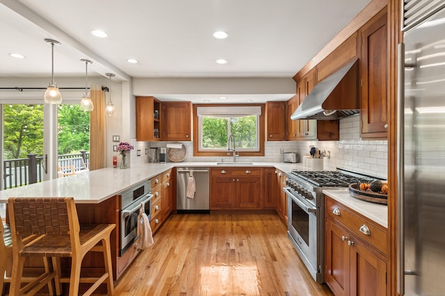 19 Huckleberry Dr S, Norwalk, CT 06850 - kitchen with high end appliances, open shelves, a peninsula, wall chimney exhaust hood, and brown cabinetry
