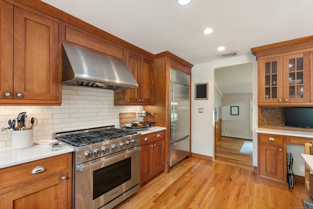 19 Huckleberry Dr S, Norwalk, CT 06850 - kitchen with high quality appliances, wall chimney range hood, brown cabinetry, light countertops, and recessed lighting