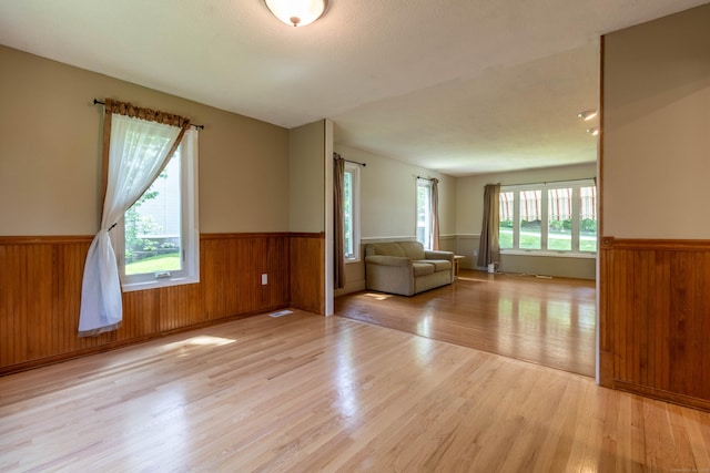 131 Spring Brook Dr, Middletown, CT 06457 - unfurnished living room featuring wainscoting, light wood finished floors, and wood walls