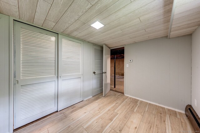 33 White Oak Ln, Woodbridge, CT 06525 - unfurnished bedroom featuring a baseboard radiator, light wood-style flooring, wooden ceiling, and baseboards
