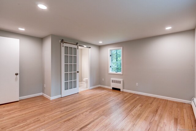 33 White Oak Ln, Woodbridge, CT 06525 - spare room with radiator, a barn door, light wood-style flooring, recessed lighting, and baseboards