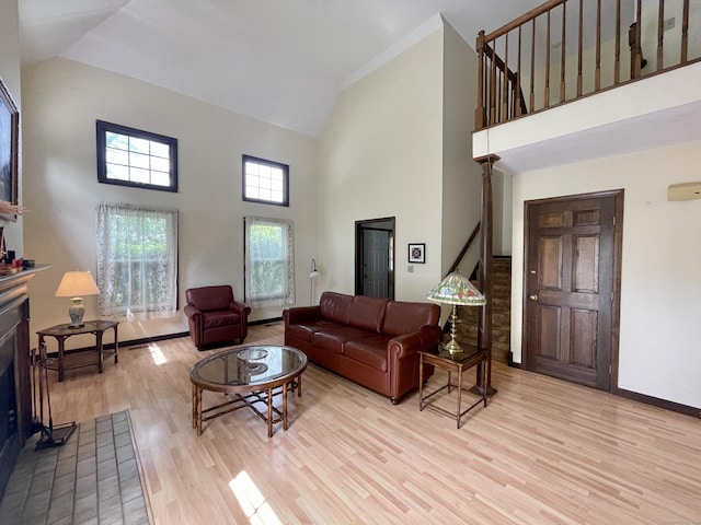 1433 Naugatuck Ave Unit 1433, Milford, CT 06461 - living room featuring high vaulted ceiling, a fireplace with flush hearth, light wood finished floors, stairs, and baseboards