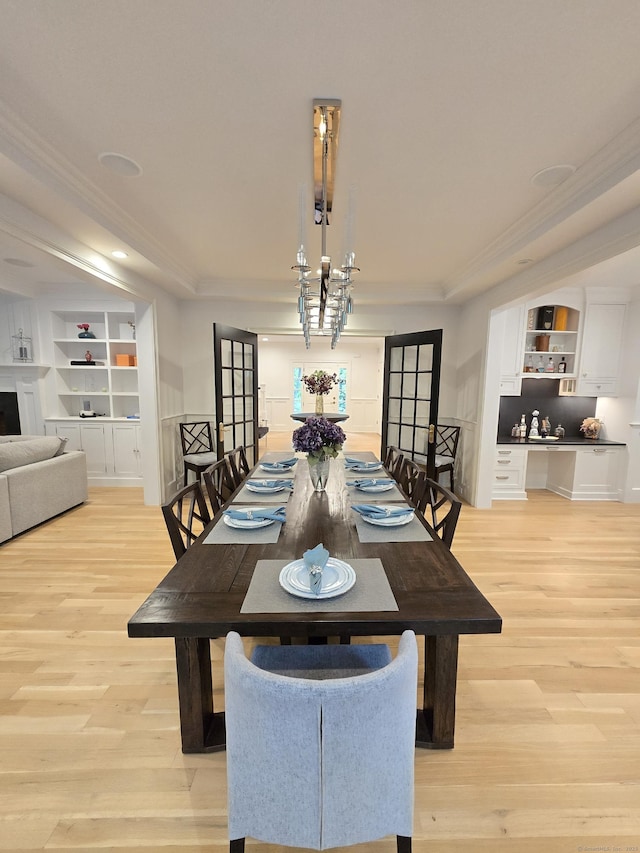 20 Crawford Rd, Westport, CT 06880 - dining area with crown molding, light wood finished floors, built in shelves, a chandelier, and a tray ceiling