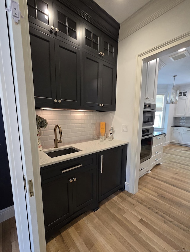 20 Crawford Rd, Westport, CT 06880 - bar area featuring a sink, light wood finished floors, tasteful backsplash, ornamental molding, and baseboards