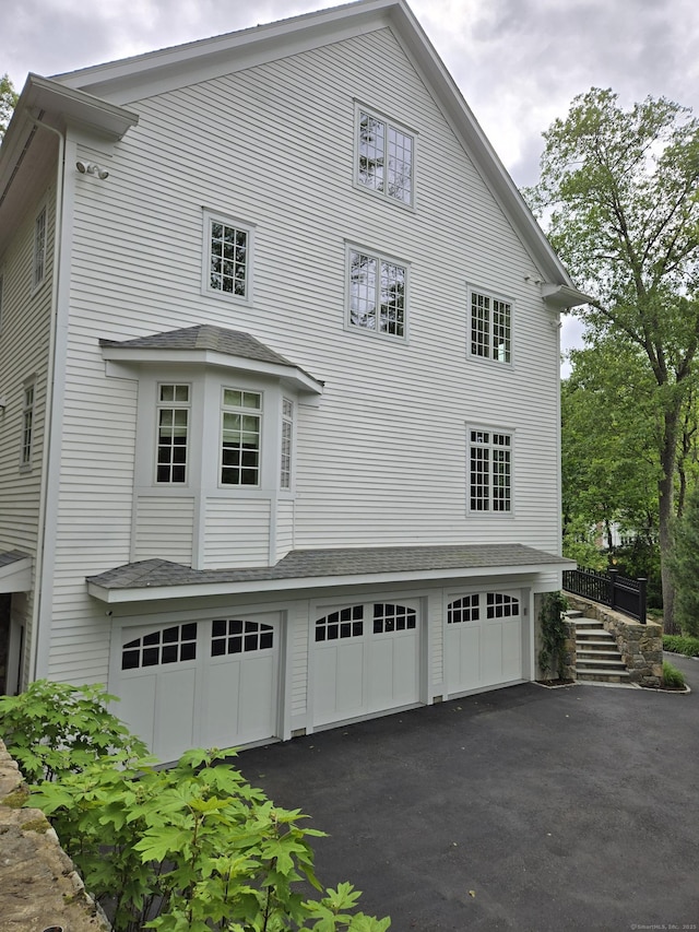 20 Crawford Rd, Westport, CT 06880 - view of side of property with driveway, a garage, stairway, and roof with shingles