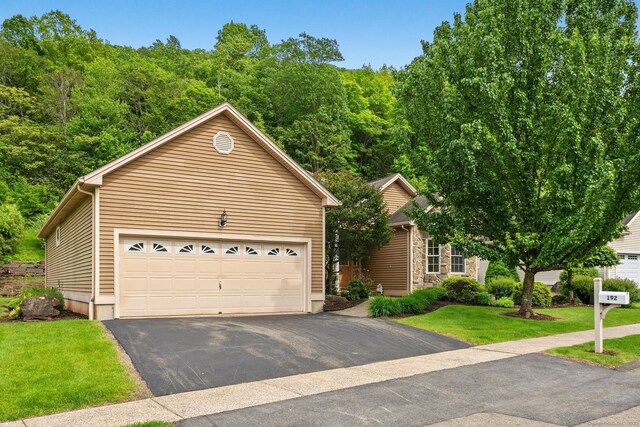 192 Rosewood Ln Unit 192, Berlin, CT 06037 - view of front of home with a garage, a front yard, stone siding, and a wooded view