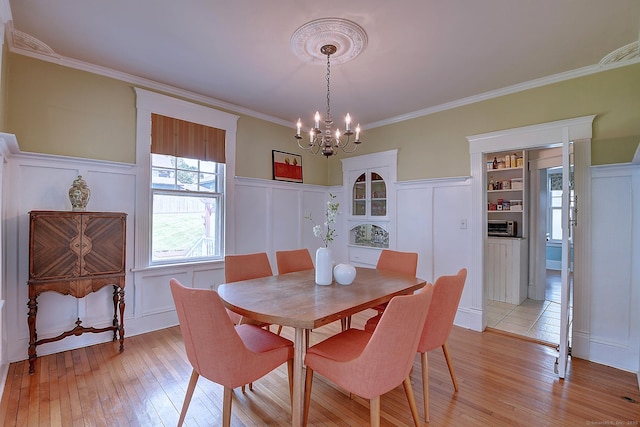 59 Golf St, Newington, CT 06111 - dining area featuring a decorative wall, a chandelier, light wood-type flooring, crown molding, and wainscoting