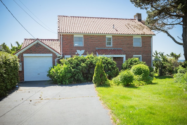 28 Morgan Ter, East Haven, CT 06512 - view of front facade with a tile roof, driveway, a chimney, a front yard, and brick siding