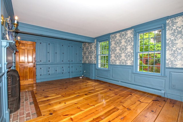 440 Mapleton Ave, Suffield, CT 06078 - unfurnished living room featuring wood-type flooring, wallpapered walls, a baseboard heating unit, crown molding, and wainscoting