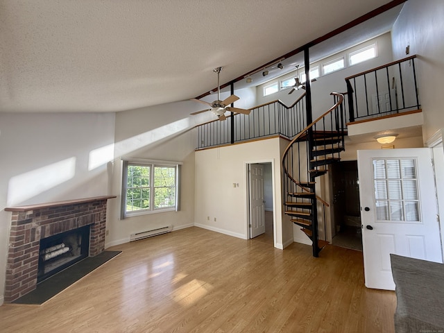 102 Beard Dr Unit 102, New Milford, CT 06776 - unfurnished living room with a baseboard heating unit, ceiling fan, a fireplace, wood finished floors, and stairs