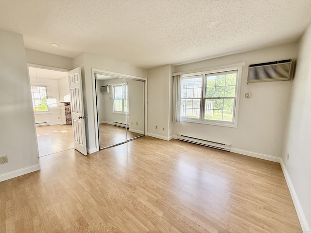 102 Beard Dr Unit 102, New Milford, CT 06776 - empty room featuring a baseboard heating unit, a wall mounted AC, a textured ceiling, and light wood-style floors
