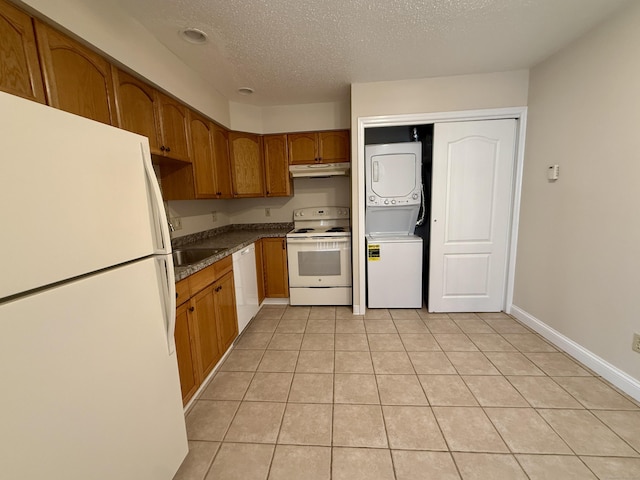 102 Beard Dr Unit 102, New Milford, CT 06776 - kitchen with white appliances, stacked washer / dryer, under cabinet range hood, a textured ceiling, and brown cabinetry