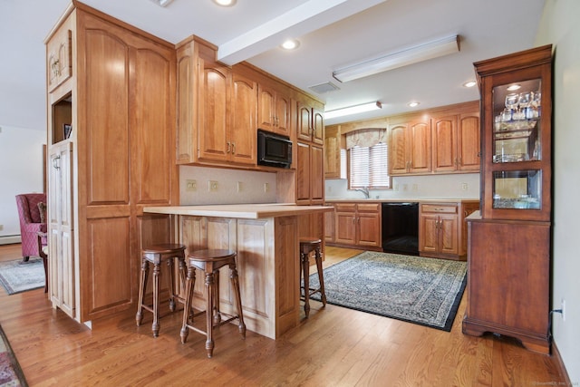 40 Holmes St, Stonington, CT 06355 - kitchen featuring black appliances, a kitchen bar, light wood-type flooring, and a peninsula