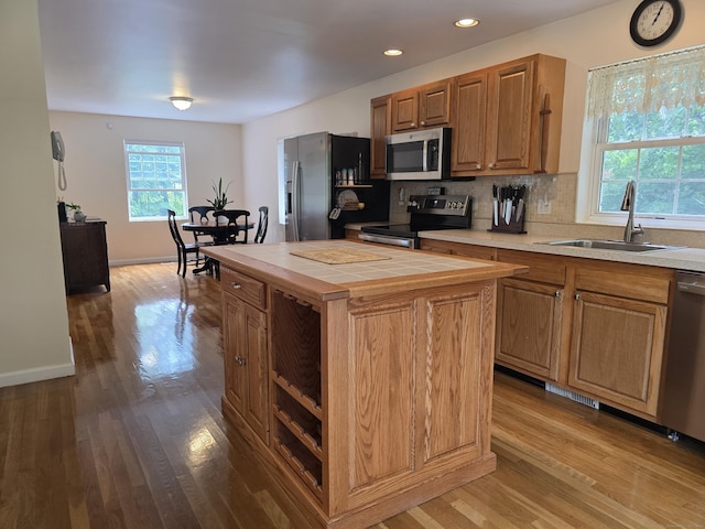 141 Grove St, Shelton, CT 06484 - kitchen featuring appliances with stainless steel finishes, tile countertops, wood finished floors, tasteful backsplash, and a kitchen island