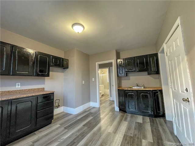 158 Martin St, Hartford, CT 06120 - kitchen featuring dark cabinetry, light wood-style flooring, baseboards, a sink, and light countertops