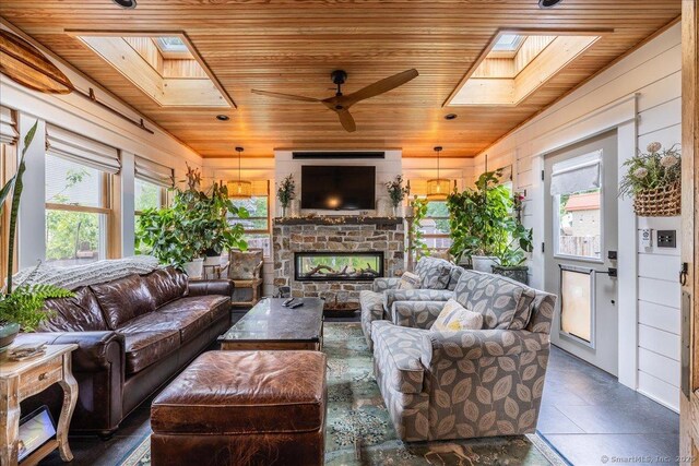 311 Captain Thomas Blvd, West Haven, CT 06516 - living room with wood ceiling, a skylight, a fireplace, a ceiling fan, and wooden walls