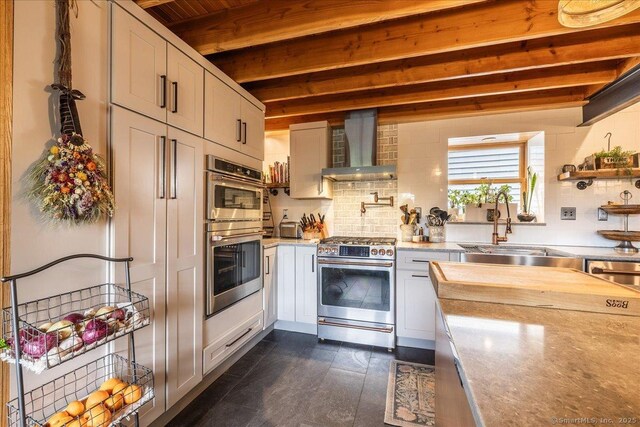 311 Captain Thomas Blvd, West Haven, CT 06516 - kitchen featuring wall chimney exhaust hood, appliances with stainless steel finishes, beam ceiling, a sink, and decorative backsplash