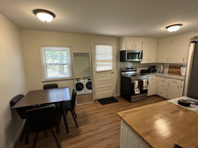 1188 Worthington Rdg, Berlin, CT 06037 - kitchen with stainless steel appliances, washing machine and dryer, white cabinets, dark wood-type flooring, and decorative backsplash