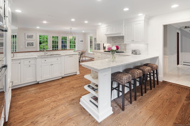 104 Cheesespring Rd, Wilton, CT 06897 - kitchen featuring a sink, a peninsula, white cabinets, light wood finished floors, and a kitchen breakfast bar
