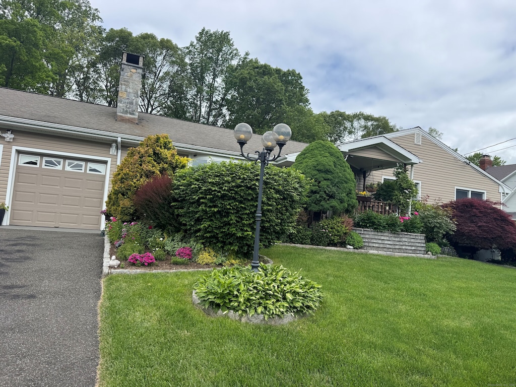 91 Lounsbury Rd, Trumbull, CT 06611 - view of front of house featuring a front lawn, an attached garage, a chimney, and asphalt driveway