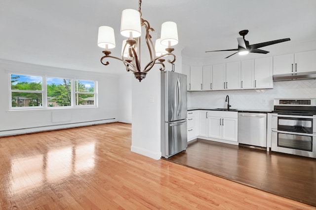 71 Mountain Laurel Dr Unit 71, Wethersfield, CT 06109 - kitchen with appliances with stainless steel finishes, under cabinet range hood, a sink, a baseboard radiator, and a chandelier