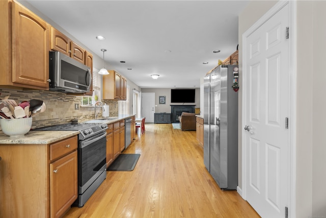 12 Colonial Heights Rd, East Haven, CT 06473 - kitchen featuring appliances with stainless steel finishes, open floor plan, tasteful backsplash, a fireplace, and light wood-type flooring