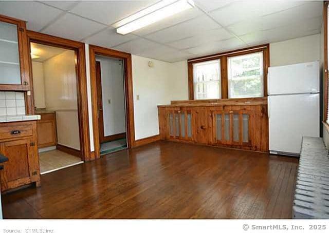33 Silver St, Branford, CT 06405 - kitchen with freestanding refrigerator, dark wood-type flooring, a paneled ceiling, glass insert cabinets, and brown cabinetry