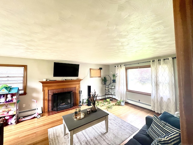 27 Eton Pl, New Britain, CT 06053 - living room with a baseboard radiator, wood finished floors, a textured ceiling, a brick fireplace, and a baseboard heating unit