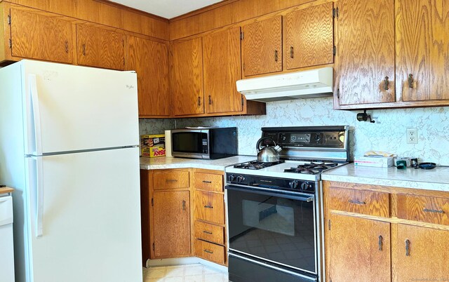 100 Arcadia Ave, Stratford, CT 06614 - kitchen with freestanding refrigerator, range with gas cooktop, stainless steel microwave, under cabinet range hood, and backsplash