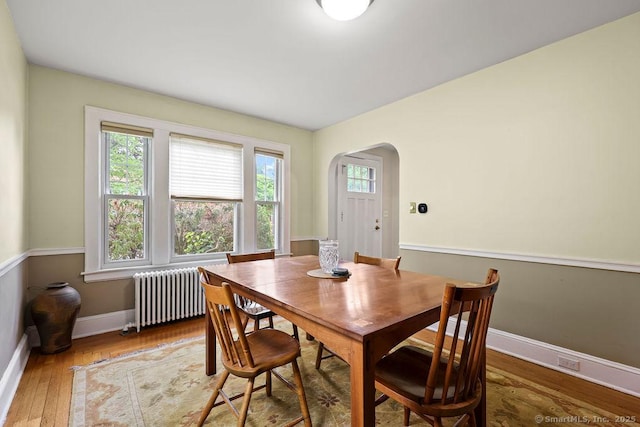 33 Bellevue Pl, Middletown, CT 06457 - dining space with radiator, arched walkways, wood finished floors, and baseboards