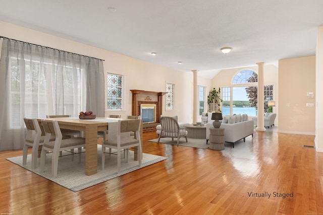8 Wadsworth Ln, Waterford, CT 06385 - dining area featuring decorative columns, light wood-style floors, a glass covered fireplace, lofted ceiling, and baseboards