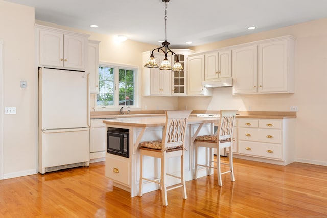 8 Wadsworth Ln, Waterford, CT 06385 - kitchen featuring freestanding refrigerator, under cabinet range hood, light wood finished floors, a chandelier, and a breakfast bar area