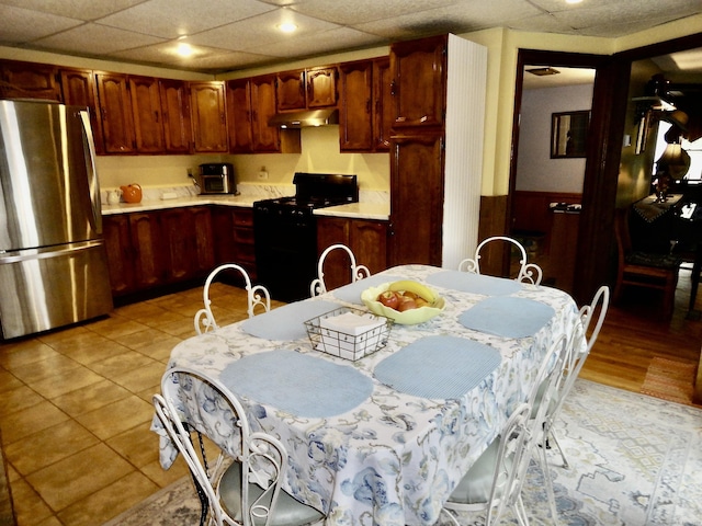 409 N Main St, Winchester, CT 06098 - kitchen featuring freestanding refrigerator, black range oven, under cabinet range hood, light countertops, and wainscoting