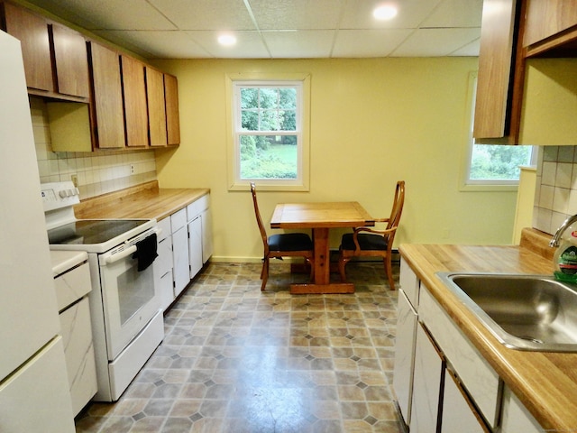 409 N Main St, Winchester, CT 06098 - kitchen with white appliances, tasteful backsplash, light countertops, plenty of natural light, and a paneled ceiling
