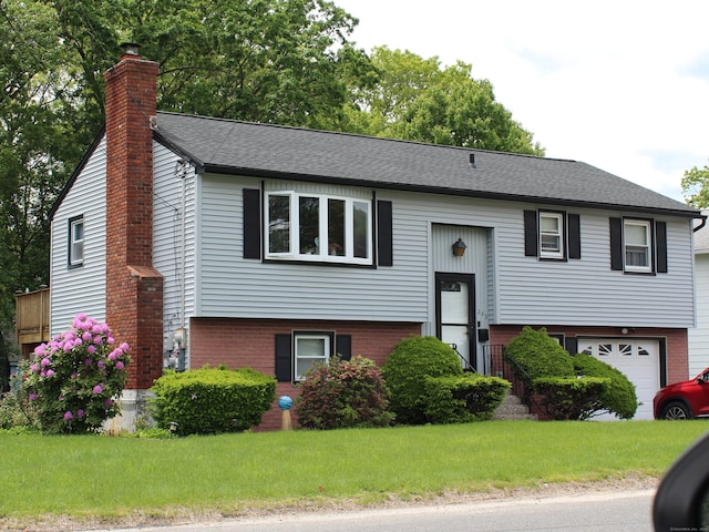 243 Courtland Ave, Waterbury, CT 06705 - bi-level home featuring a chimney, an attached garage, a front yard, and brick siding