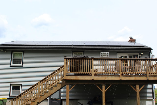 243 Courtland Ave, Waterbury, CT 06705 - back of property featuring a wooden deck, roof mounted solar panels, stairs, and a chimney