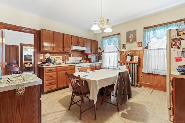 30 Newton St, Hartford, CT 06106 - kitchen with under cabinet range hood, white gas stove, a chandelier, light countertops, and a wainscoted wall