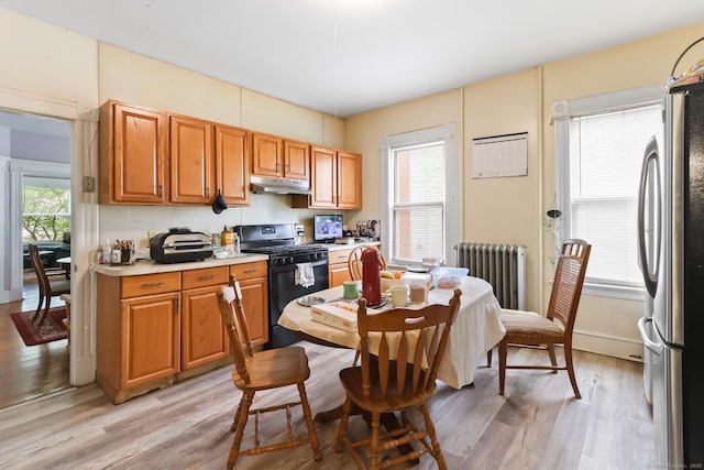 30 Newton St, Hartford, CT 06106 - kitchen featuring black range with gas cooktop, radiator heating unit, under cabinet range hood, freestanding refrigerator, and light wood-style floors